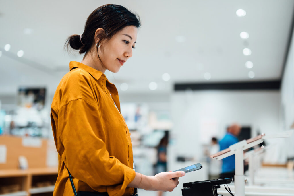 Woman uses phone to pay at store.